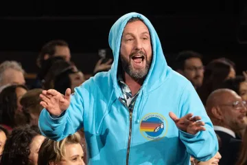 Adam Sandler in a blue hoodie at the Oscars, surrounded by audience members.