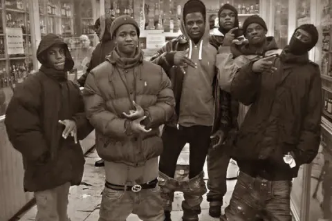 Group of young men posing in a store with serious expressions.