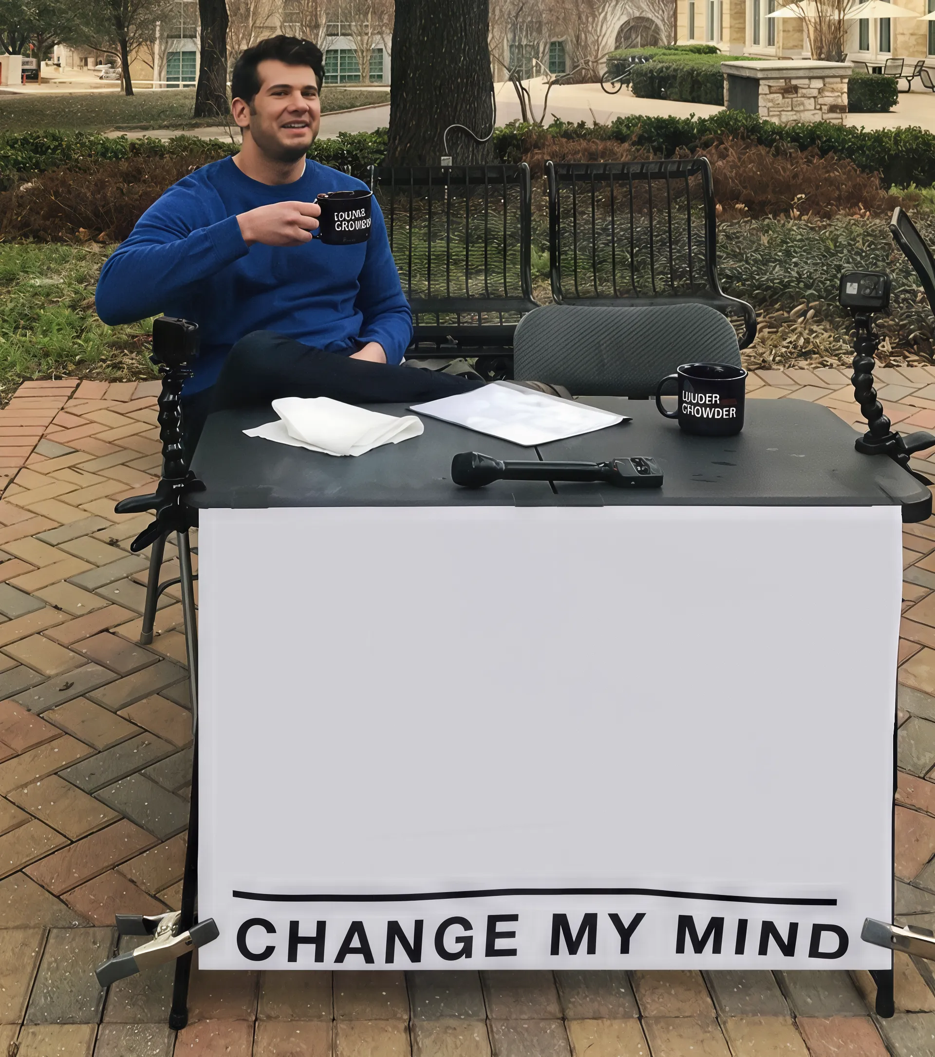 Man sitting at a table with a sign that reads 'Change My Mind'.