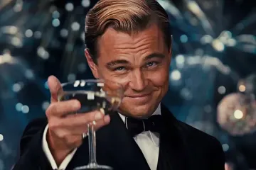 Leonardo DiCaprio in a tuxedo raising a champagne glass with a smile.