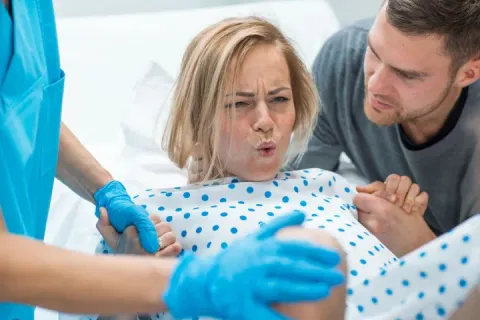 Woman in labor with supportive partner and medical staff