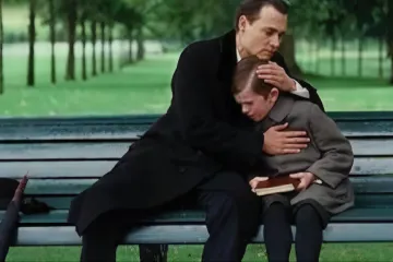 A man and a young boy sitting on a park bench, having a heartfelt conversation.