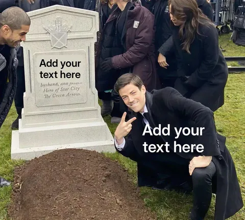 Man in a suit crouching and posing with a peace sign next to a grave.