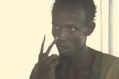 Man pointing at his eyes with a serious expression in a bright room.