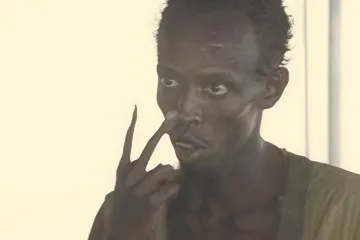 Man pointing at his eyes with a serious expression in a bright room.