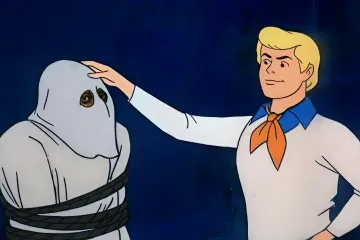 Fred revealing a masked villain in Scooby-Doo cartoon.