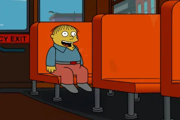 Ralph Wiggum sitting on a school bus with an emergency exit sign behind him.
