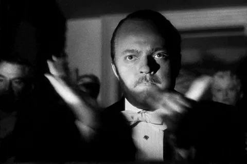 Black and white image of a man in a suit performing a slow clap.