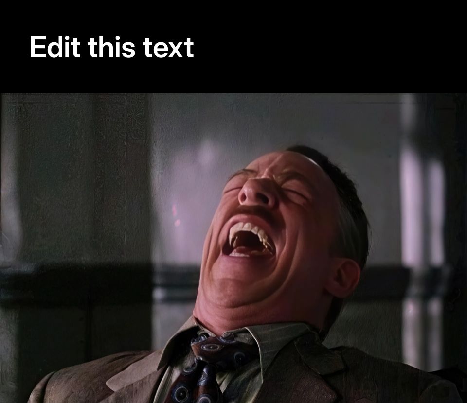 A man in a suit laughing heartily in an office setting.