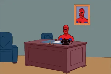 Spider-man sitting at a desk with a framed picture of himself on the wall.