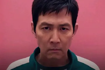 Two images of a man in a green tracksuit, smiling and then serious, against a pink background.