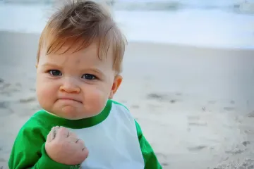 A determined baby with a clenched fist on the beach.