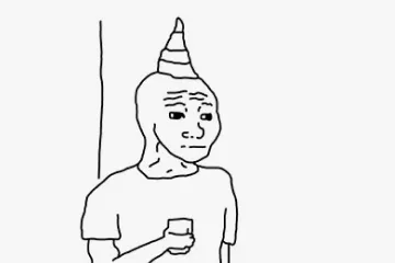 A person with a party hat standing alone at a party, holding a drink, while others dance.