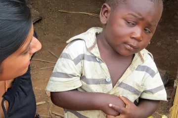 A young boy with a skeptical expression looking at a woman in a rural setting.