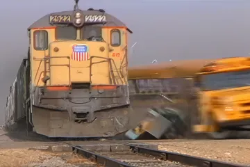 Train colliding with a yellow school bus at a railway crossing.