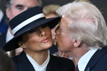 Donald Trump kisses Melania Trump, who is wearing a wide-brimmed hat.