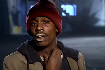 A man in a red beanie and brown jacket looking desperate.