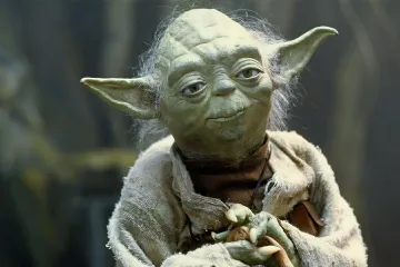 Yoda from Star Wars with a wise expression, holding a cane.