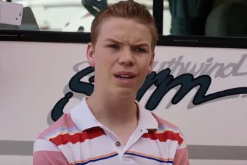 Young man in a striped shirt looking surprised near a bus.